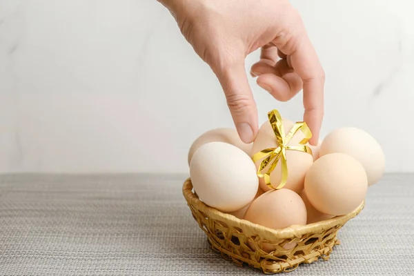 Woman Hand Puts Chicken Egg Tied Festive Ribbon Basket Other — стоковое фото