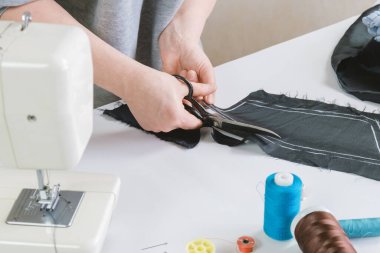 Terzi kadın kumaşı metal terzi makasıyla keser. Terzi, gelecekteki kumaş ürünleri için bir model oluşturuyor. Bir moda tasarımcısının işyeri