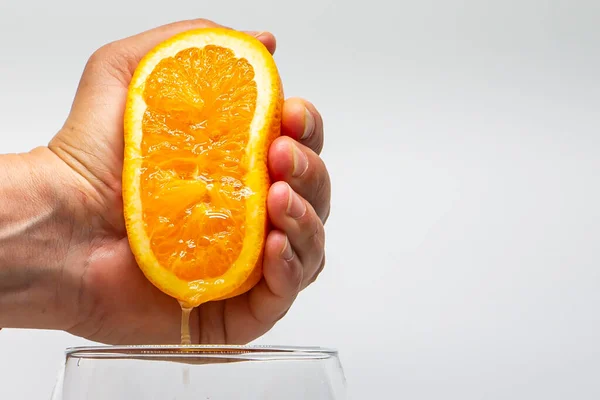 Macro photo of an orange squeezed with a hand. Orange juice. Side photo. Citrus fruit juice. Natural juices.