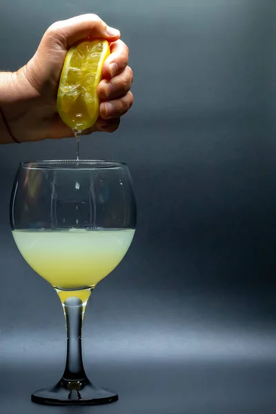 Lemon juice with glass cup. Hand squeezing a lemon in a glass cup. Citrus. Natural juices