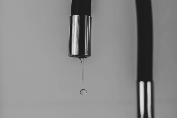 Drop of water falling from a faucet. Water restrictions due to drought. Scarce of water. Limitations of water consumption.