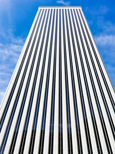 Black and white building with linear structure. White skyscraper with blue sky. Building in business area. Cityscape.