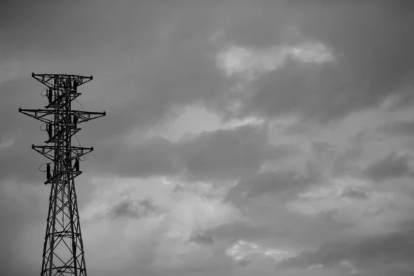 High tension towers on the gray sky. Storm clouds. Black and white photo. Sky covered with storm clouds.