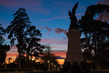 İspanya 'nın Madrid şehrindeki Retiro Park' ta bulunan Fallen Angel 'ın halka açık heykeli. Heykel, muhteşem bir günbatımında güzel turuncu ve mavi bir ışık tarafından aydınlatılır. Doğru.