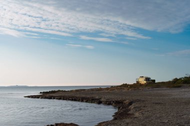Akdeniz kıyısında güzel bir koyun yanına park edilmiş klasik bir karavan..
