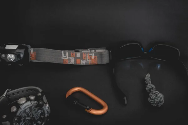 Flatlay from a bunch of Outdoor equipment,  on a dark background.