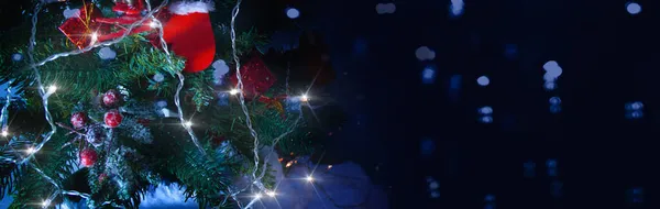 Arka planda bir hediye ve bulanık bir arka planda süslenmiş Noel ağacı.