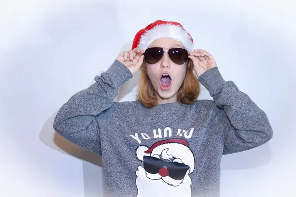 Genç kızıl saçlı bir kız gülümsüyor ve kameraya bakıyor. Kızıl saçlı bir öğrenci Noel hediyelerinde böyle indirimler görünce çok şaşırır. Mavi kazaklı çilli bir kız öğrenci şok olur.