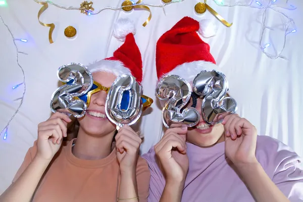 Noel Baba ya da Noel Baba şapkalı iki genç. Komik gözlüklü, 2022 yılının rakamlarıyla.