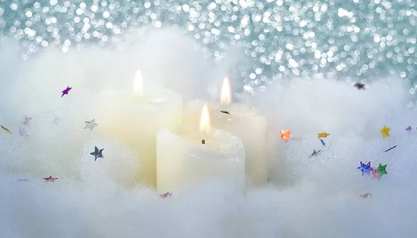 Рождественские горящие свечи на пушистом белом снегу на блестящем фоне. Свечи, свечи с рождественским декором. — стоковое фото
