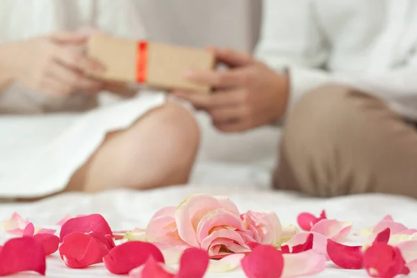 Ön planda gül yaprakları. Arka plandaki çift hediyeler veriyor..