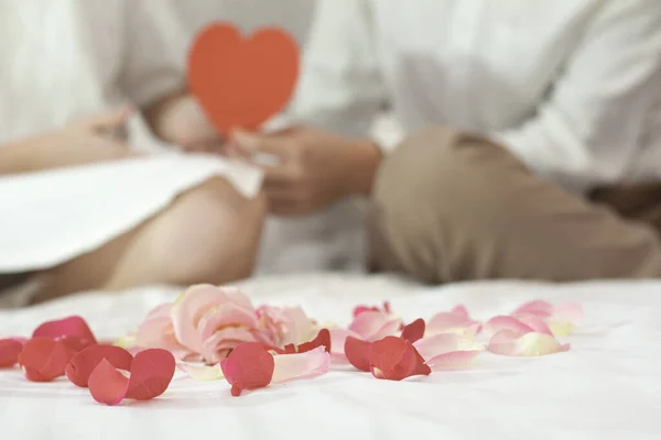 Ön planda gül yaprakları. Arka plandaki çift hediyeler veriyor..