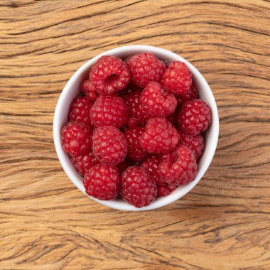 Ahşap masanın üzerinde bir kasede ahududu.