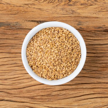 Tahta masanın üzerinde bir kasede keten tohumu.