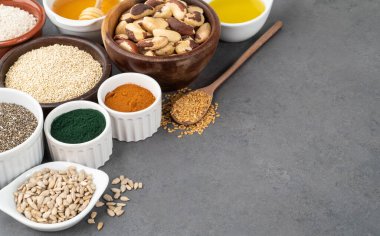 Taş zemin üzerinde fotokopi alanı olan kaşıklarla çeşitli süper yiyecekler. Chia, kinoa, yulaf, keten tohumu, bal, spirulina ve diğerleri..