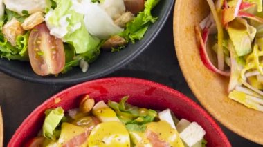 Renkli kaseler üzerinde dönen salatalar, üst görünüm.