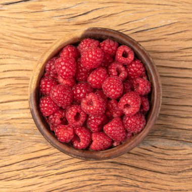 Ahşap masanın üzerinde bir kasede ahududu.