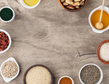 Fotokopi alanı olan ahşap arka planda çeşitli süper yiyecekler. Chia, kinoa, yulaf, keten tohumu, bal, spirulina ve diğerleri..