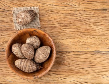 Ahşap bir masanın üzerinde çiğ yer elması ya da rezalet.