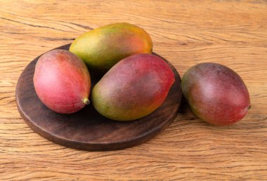 Ahşap tahtanın üzerinde bir grup olgun mango.