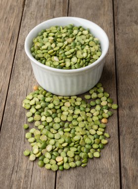 Tahta masanın üzerinde bir kasede çiğ yeşil bezelye..