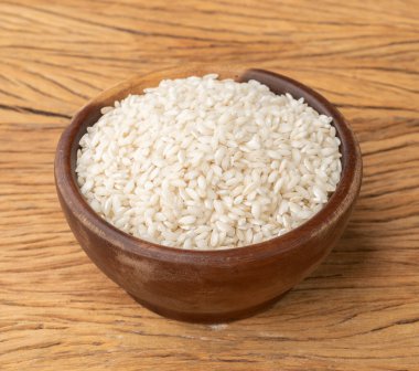 Çiğ carnaroli risotto pilavı ahşap masanın üzerinde bir kasede.