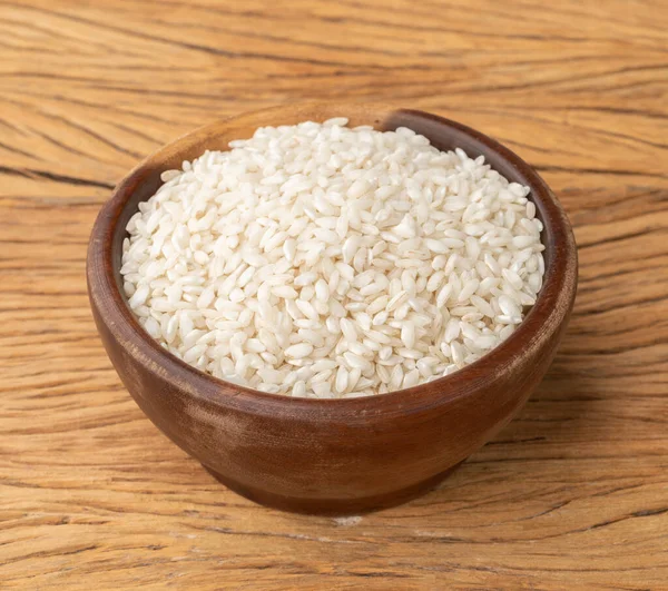 Çiğ carnaroli risotto pilavı ahşap masanın üzerinde bir kasede.