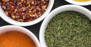 Closeup of assorted colorful spices in white bowls.
