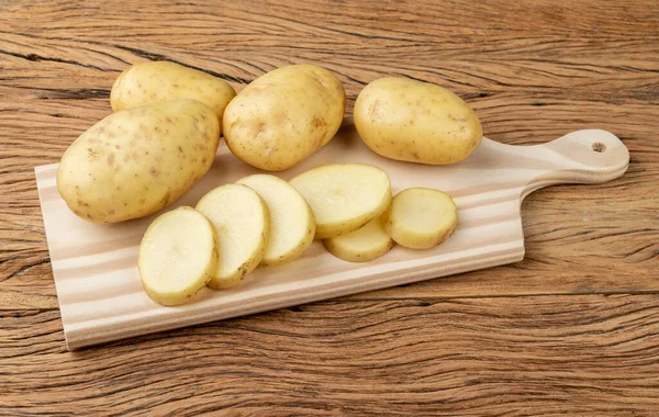 Batatas Cruas Com Fatias Uma Tábua Corte Sobre Mesa Madeira — Fotografia de Stock
