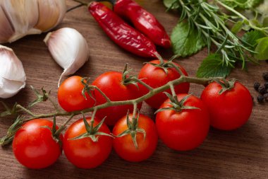 Domates, sarımsak, biber ve otlar ahşap masanın üzerinde..