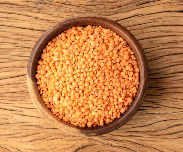 Tahta masanın üzerinde bir kasede turuncu mercimek..