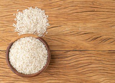 Ahşap bir masanın üzerinde, içinde fotokopi alanı olan çiğ carnaroli risotto pilavı..