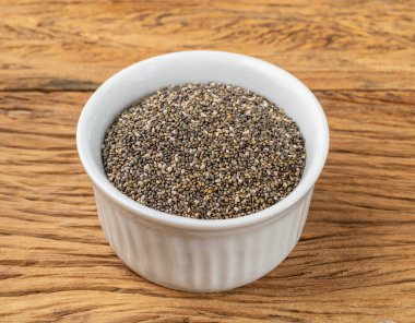 Tahta masanın üzerinde beyaz bir kasede Chia tohumları.