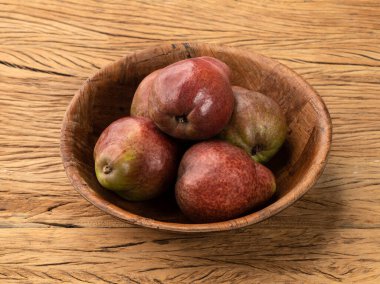 Ahşap masanın üzerinde kırmızı armutlar..