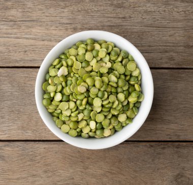 Tahta masanın üzerinde bir kasede çiğ yeşil bezelye..