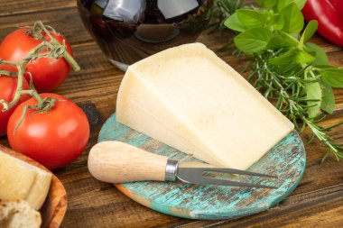 Parmesan peyniri, domates, zeytinyağı, şarap, ekmek ve otlar ahşap masanın üzerinde. Akdeniz yemekleri.