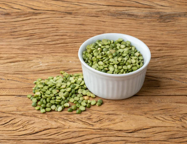 Tahta masanın üzerinde bir kasede çiğ yeşil bezelye..