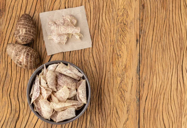 Tahta masa üzerinde çiğ sebze ve fotokopi alanı olan bir kasede patates cipsi ya da taro cipsi..