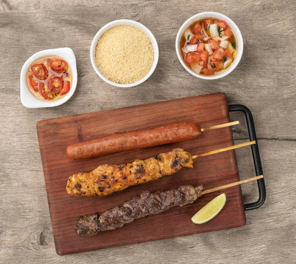 Tahta üzerinde et, tavuk ve domuz sosisi şişleri ve faraigrette sosu..