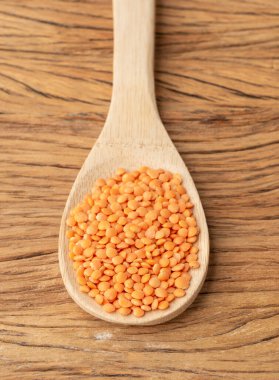 Tahta masanın üzerinde bir kaşık üzerinde turuncu mercimek.