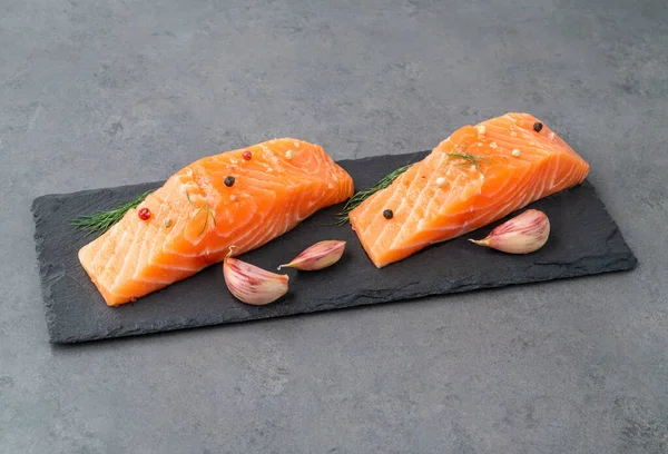 Taş tahtanın üzerinde baharatlı çiğ somon dilimleri..