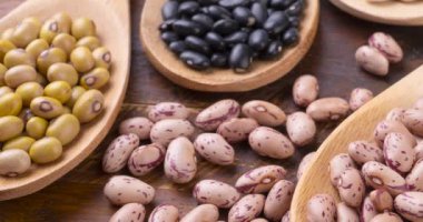 Tahta masanın üzerinde kaşık üzerinde çeşitli fasulyeler..