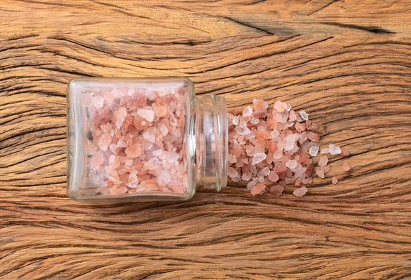 在木制桌子上的玻璃壶里塞满了粉红的希玛拉盐 — 图库照片