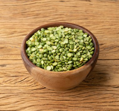 Tahta masanın üzerinde bir kasede çiğ yeşil bezelye..