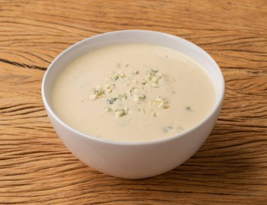 Tahta masanın üzerinde bir kasede peynir çorbası..