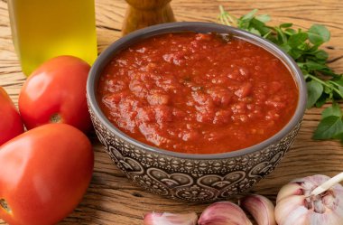 Domates sosu, domates, sarımsak, zeytinyağı ve otlar ahşap masanın üzerinde..