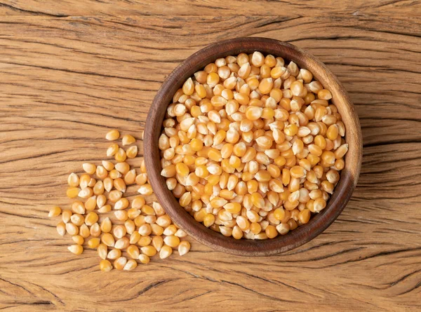 Dried corn or popcorn grains in a bowl over wooden table.