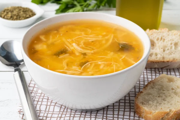 Tabakta tavuk çorbası, ekmek dilimleri ve ahşap masa üzerinde baharat..