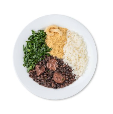 Beyaz arka planda, pirinç, farofa, lahana ve çıtırtılarla izole edilmiş bir tabakta tipik Brezilya feijoadası..