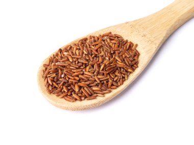 Beyaz arka planda izole edilmiş kaşıkta çiğ kırmızı pirinç..